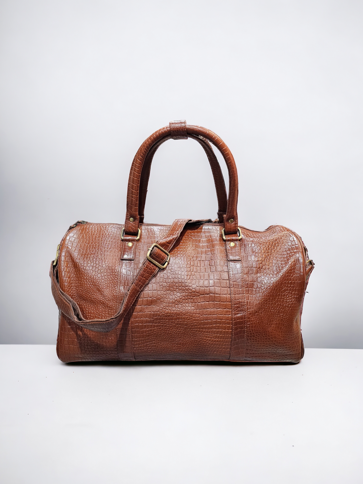 Small brown leather duffel bag with croco pattern, adjustable shoulder strap, and multiple compartments. Durable and stylish, perfect for short trips and everyday use.