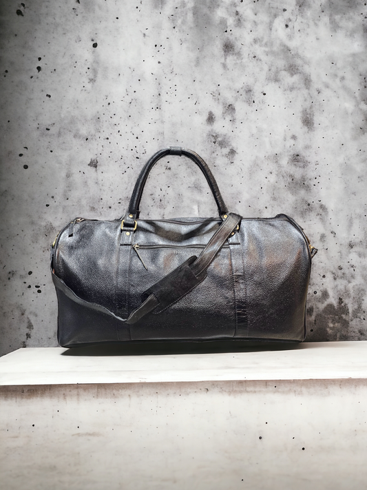 Large black leather duffel bag with multiple compartments, adjustable shoulder strap, and sturdy handles. Ideal for travel, with durable construction and sleek design.