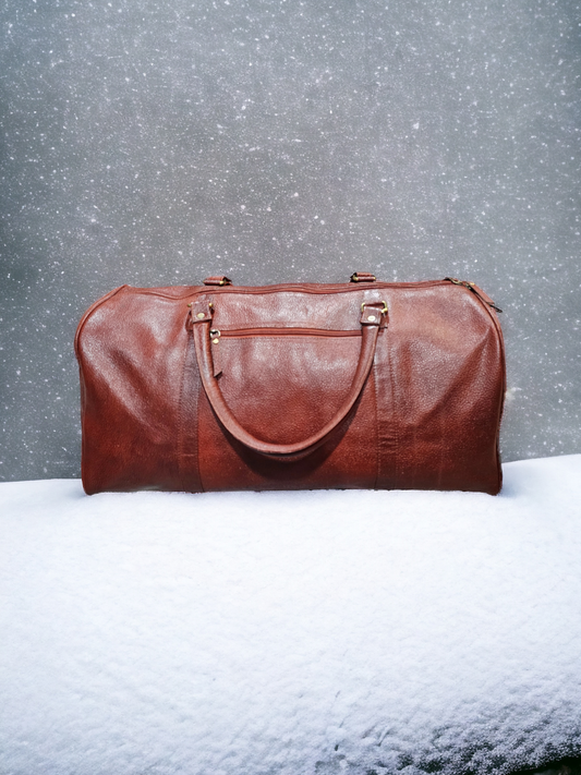 Large brown leather duffel bag with adjustable shoulder strap, sturdy handles, and spacious compartments. Durable and stylish, perfect for extended trips.