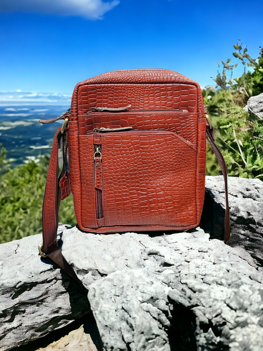 Rust leather sling bag with croco print, adjustable strap, and multiple zippered compartments. Compact, stylish, and perfect for daily essentials.